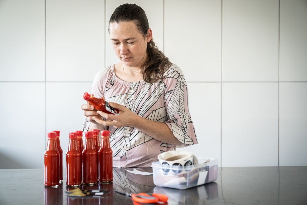 Francine Klug Schimmelpfennig cola manualmente os rótulos dos pimentões produzidos na propriedade — Foto: Marcelo Curia